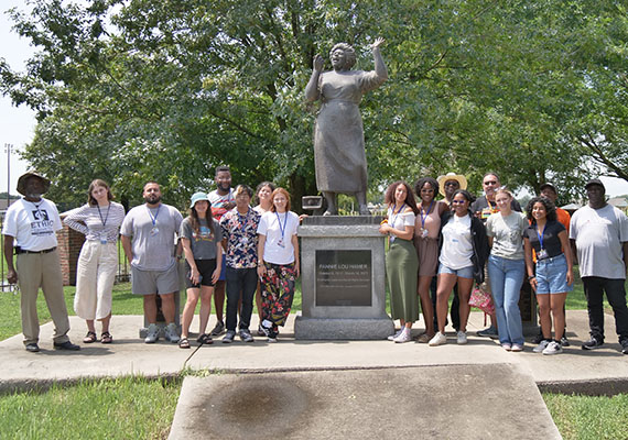 a group of people posing for a photo in front of a statue.